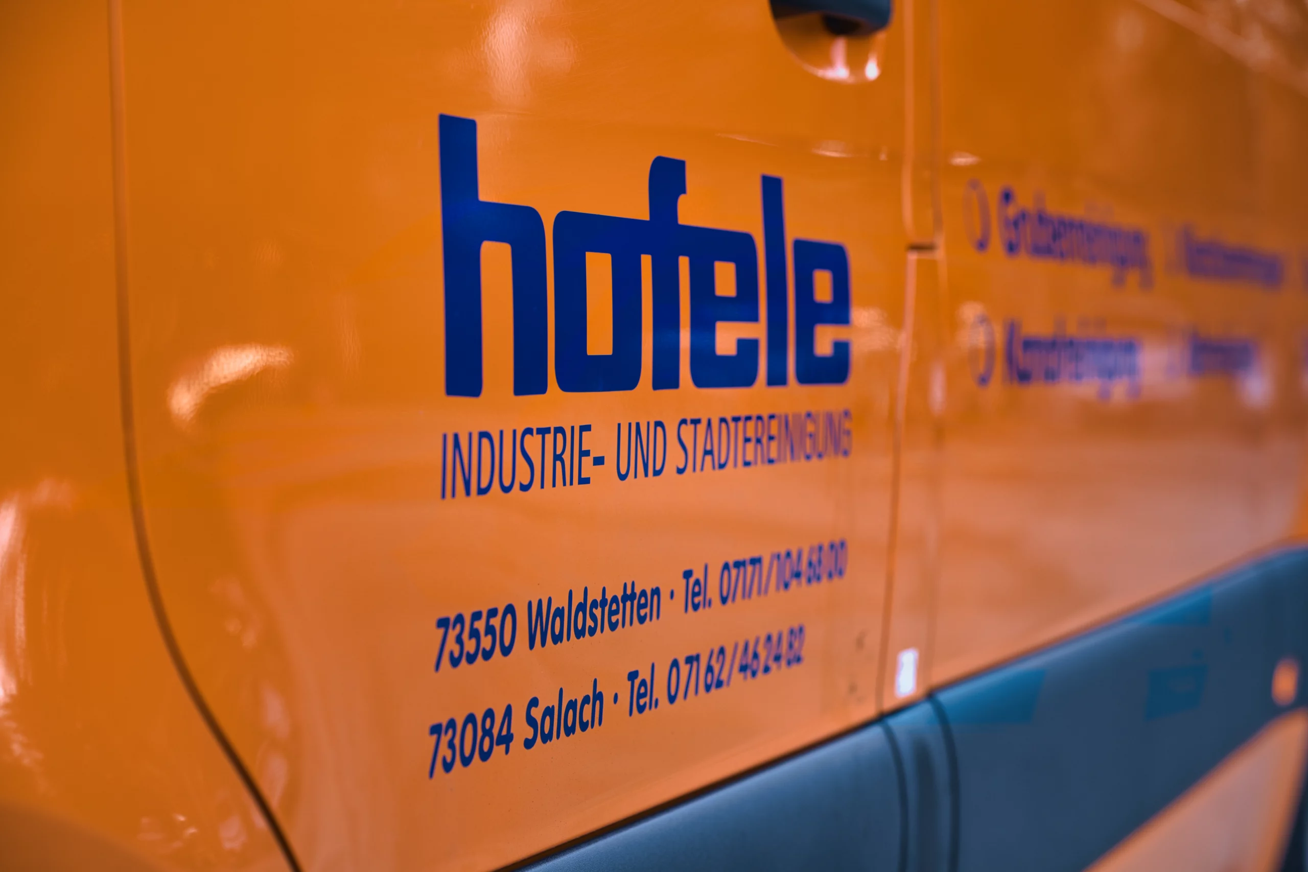 Detailaufnahme der Hofele Fahrzeugbeschriftung auf orangefarbenem Einsatzfahrzeug