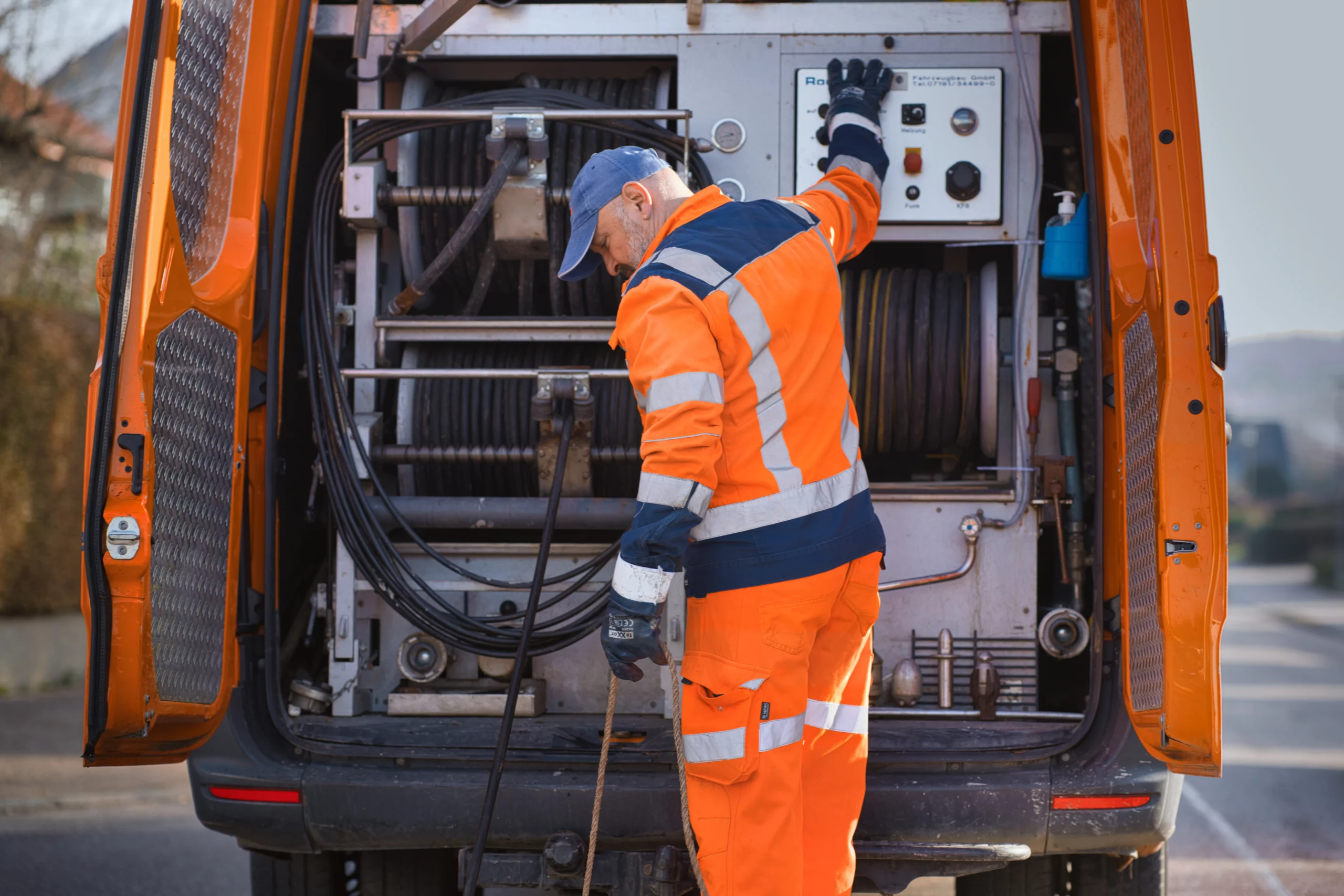 Dichtheitsprüfung mit professioneller Prüftechnik Mitarbeiter in orangefarbener Arbeitskleidung bei der Dichtheitsprüfung am Inspektionsfahrzeug