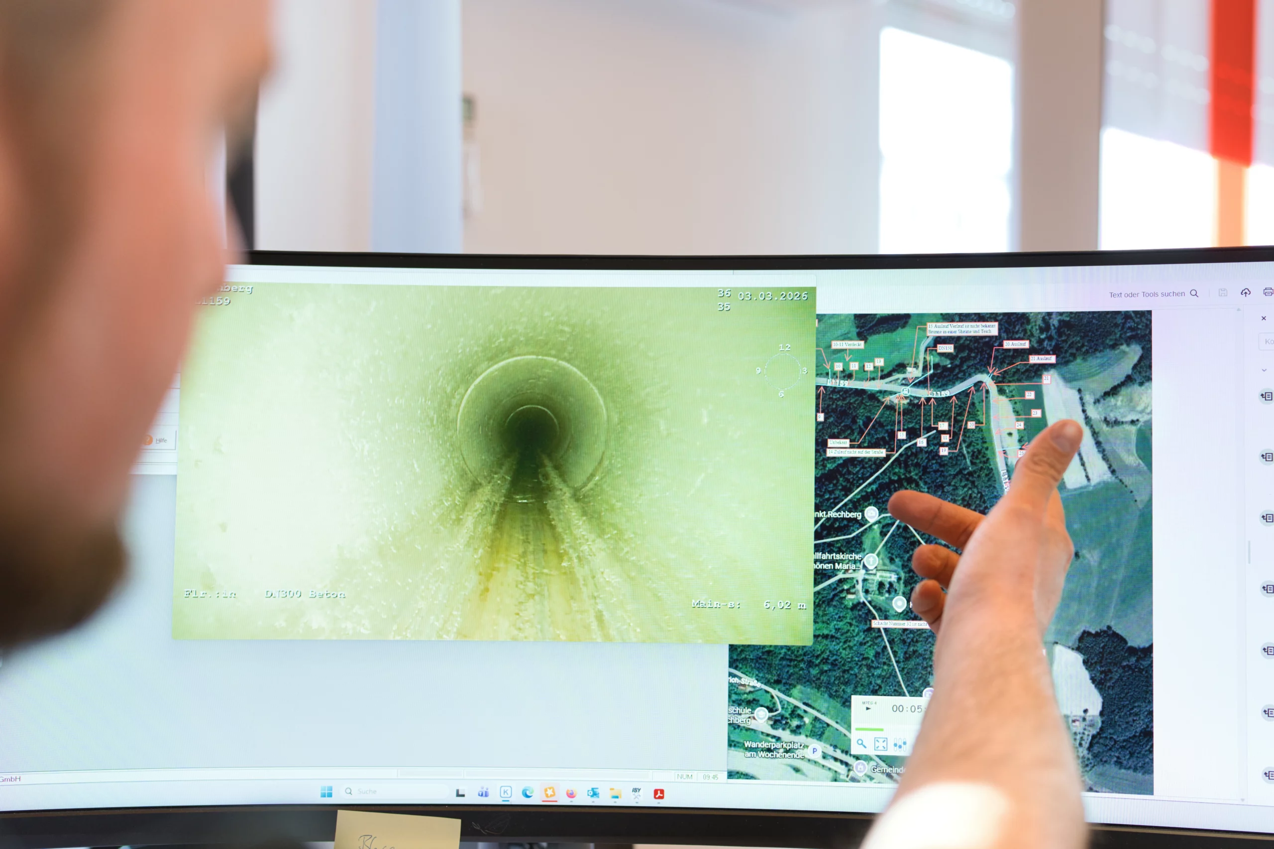 Professionelle Kanal-TV-Inspektion bei Hofele zur Schadensanalyse Bildschirmansicht einer Kanal-TV-Kamera und einer Satellitenkarte, auf die eine Hand zeigt, für die Rohrreinigungsdiagnose.